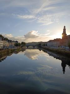 a river in a city with a clock tower in the distance at Appartement Duplex The Lighthouse in Châteaulin