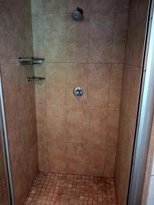 a shower with a glass door and a tiled floor at Pennywhistle in Eersterivier +3 photos