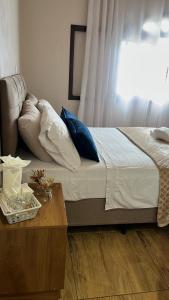 a bed with blue pillows and a table in a room at Pousada Nunes in Lauro Müller +10 photos
