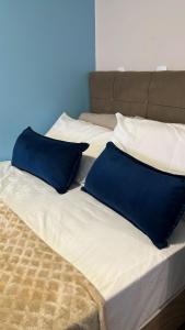 a bed with two blue pillows on top of it at Pousada Nunes in Lauro Müller