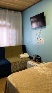 a room with two beds and a flat screen tv at Pousada Nunes in Lauro Müller