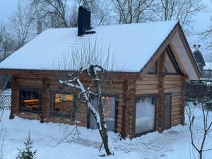 a log cabin with snow on the roof at Nordic Log-House with Sauna in Valga