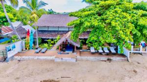 a house on the beach with chairs and a tree at Appartement vue sur mer chez VILLA AMNESYA in Nosy Be