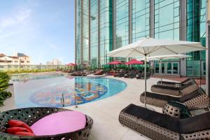a pool with chairs and an umbrella on a building at The Reverie Saigon - The Leading Hotels of the World in Ho Chi Minh City