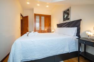 a bedroom with a large bed with white sheets at La Casina Azul de May By Silastur in San Juan de la Arena