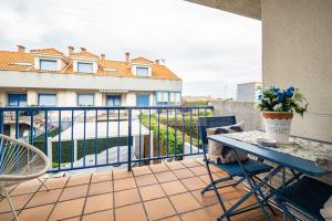 a balcony with a table and chairs and a building at La Casina Azul de May By Silastur in San Juan de la Arena