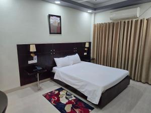 a bedroom with a bed and a table and a rug at Royal Hotel Khulna - City Center in Khulna