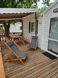 two chairs and a picnic table on a wooden deck at Mobil-home Beau Rivage in Gunsbach