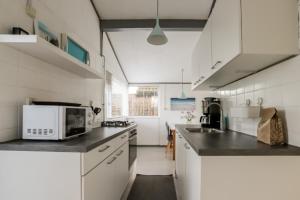 a kitchen with white cabinets and a microwave at Rekerlanden 90 in Schoorldam