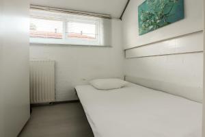 a small white room with a bed and a window at Rekerlanden 90 in Schoorldam +11 photos