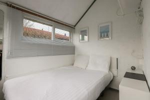 a white bedroom with a bed and a window at Rekerlanden 90 in Schoorldam