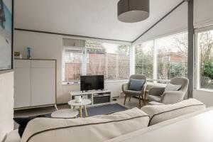 a living room with a couch and chairs and a tv at Rekerlanden 90 in Schoorldam