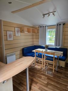 a living room with a table and a blue couch at Mobil-home Beau Rivage in Gunsbach