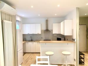 a kitchen with white cabinets and white stools at Modern 90sqm Apt - Ideal Base for Parma & Modena in Cavriago