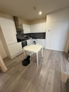 a small kitchen with a white table in a room at Kensway House in Ilford