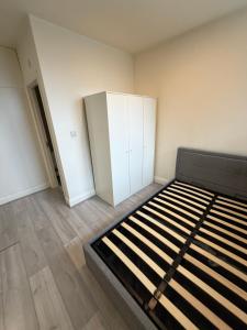 an empty room with a bed and white cabinets at Kensway House in Ilford