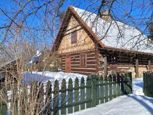 a wooden house with a fence in the snow at Hriady in Wetlina