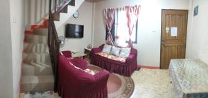 a living room with two chairs and a staircase at Eve's Place Transient Apartment in Tanay