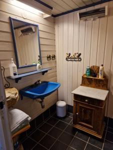 a bathroom with a blue sink and a mirror at The Old Cottage in Harstad +10 photos