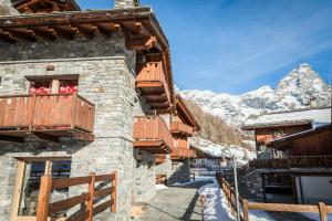 a building with wooden balconies and a snow covered mountain at Maison Carrel Elegant 7 in Breuil-Cervinia