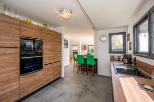 a kitchen with wooden cabinets and green chairs at Le Clos Carnonen, villa avec piscine in Quessoy