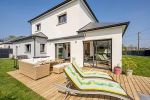 a house with a deck with chairs and a table at Le Clos Carnonen, villa avec piscine in Quessoy
