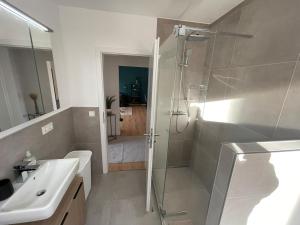 a white bathroom with a shower and a sink at Glanzvoll, moderne Wohnung in Aschaffenburg