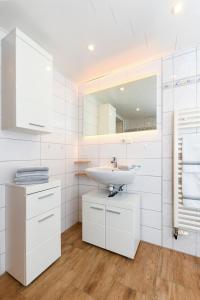 a white bathroom with a sink and a mirror at Ferienhof Gerdes in Holtgast +198 photos