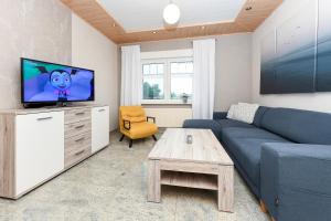 a living room with a blue couch and a tv at Ferienhof Gerdes in Holtgast