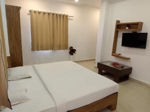 a bedroom with a white bed and a television at Infinity inn in Guna +3 photos