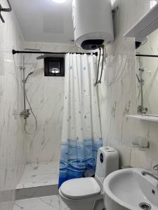 a white bathroom with a toilet and a sink at Argymak Hotel Karakol in Karakol