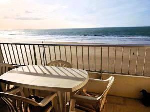 a table and chairs on a balcony overlooking the beach at Le Nid du Remblai in Les Sables-d'Olonne