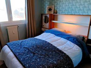 a bedroom with a bed with a blue blanket on it at Le Nid du Remblai in Les Sables-d'Olonne