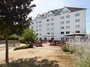 een groot wit gebouw met tafels en parasols bij Kyriad Tours - Joué-Lès-Tours in Joue-les-Tours