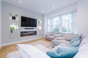 a white living room with a couch and a tv at Spring Mount - 3 Bedrooms - Close to Convention Centre in Harrogate