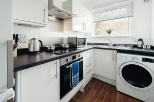 a kitchen with white cabinets and a washer and dryer at K Suites - Station Road 13 in Hinckley