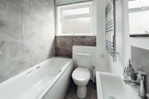 a bathroom with a toilet and a tub and a sink at K Suites - Station Road 13 in Hinckley