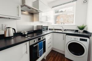 a kitchen with white cabinets and a washer and dryer at K Suites - Station Road 13 in Hinckley +8 photos