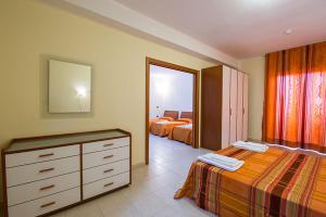 a bedroom with two beds and a dresser and a mirror at Fruit Village Capo Rizzuto S Antonio in Capo Rizzuto +21 photos
