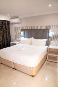 a bedroom with a large bed with white sheets and pillows at Zar Hotel in Amanzimtoti