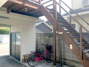Hay una bicicleta rosa estacionada junto a una escalera. en Season 1, en Naoshima
