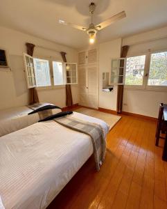 two beds in a room with wooden floors and windows at Villa Maadi 35 - R 205- Pool View Room in Cairo +33 photos