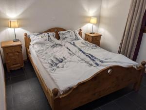 a bed in a bedroom with two nightstands and two lamps at Pointe de l'Au in Val-d'Illiez