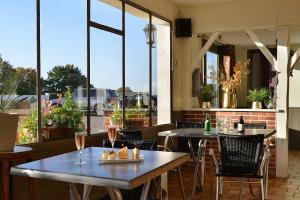 a restaurant with tables and chairs and large windows at Logis Hôtel Restaurant Berry Relais in Neuvy-Pailloux