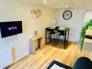 a living room with a table and a television on the wall at Appartement moderne et chaleureux in Mutrécy +5 photos
