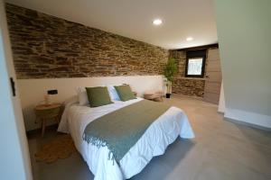 a bedroom with a bed and a brick wall at Casa Rural Lugar Vista Alegre in Lugo