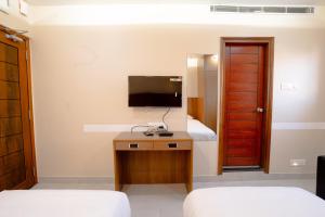 a bedroom with two beds and a tv and a desk at Hotel Orchid Imphal in Imphal