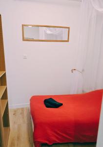 a red bed in a white room with a mirror at L'écrin médiéval in Fougères