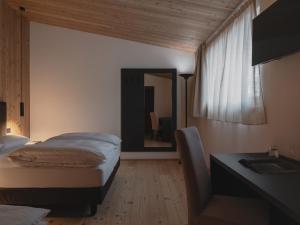 a bedroom with a bed and a desk and a mirror at Hotel Chalet Rezia in Chiesa in Valmalenco