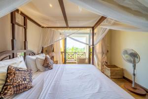 a bedroom with a canopy bed with a fan at Beat's Hideaway in Galu +21 photos